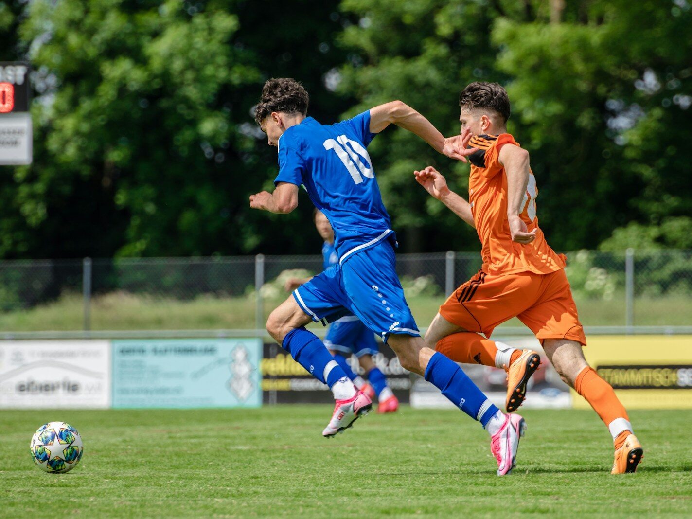 man in blue and orange jersey shirt running on green grass field during daytime